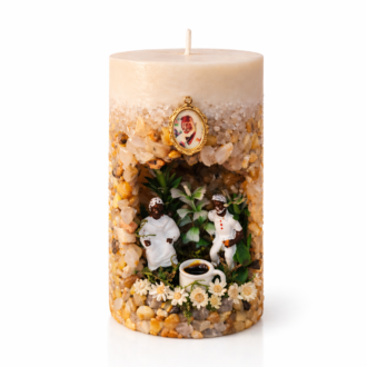 Vela artesanal Gruta dos Pretos Velhos decorada com pedras naturais, miniaturas de Pretos Velhos, flores brancas e xícara de café sobre fundo neutro.