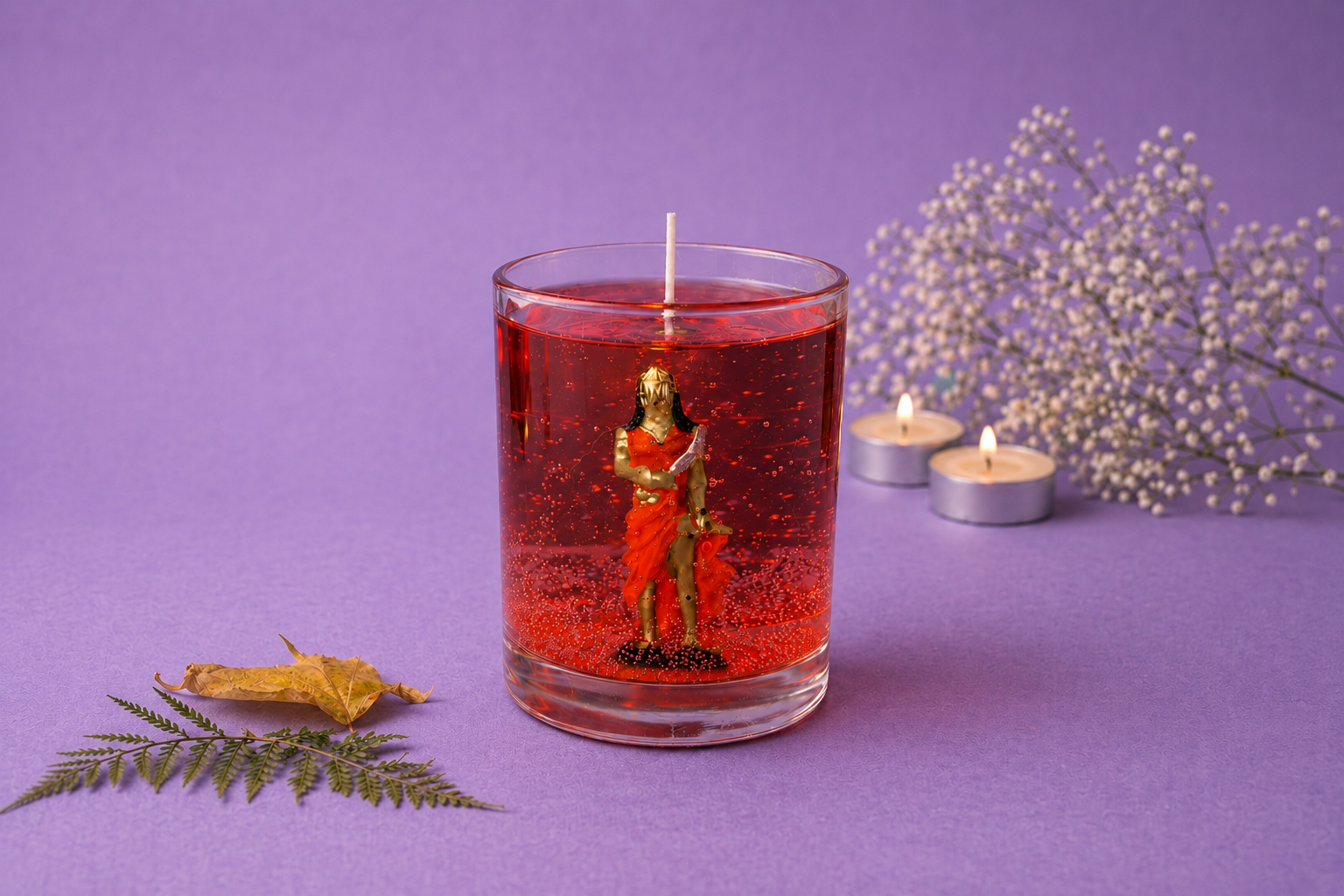 Vela em Gel Iansã artesanal em copo de vidro redondo com parafina em gel vermelha translúcida, contendo uma representação de Iansã em seu interior. A composição está sobre fundo lilás com flores delicadas, velas acesas e elementos naturais decorativos.