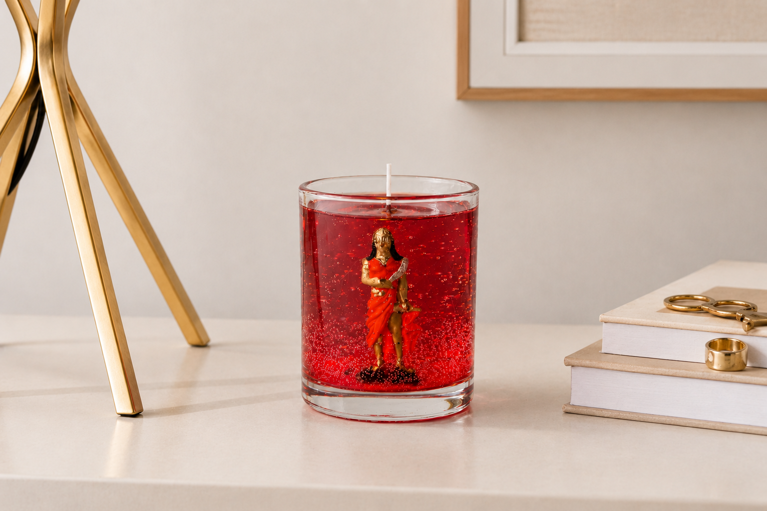 Vela em gel vermelha com imagem de Iansã encapsulada em recipiente de vidro transparente sobre mesa decorada.