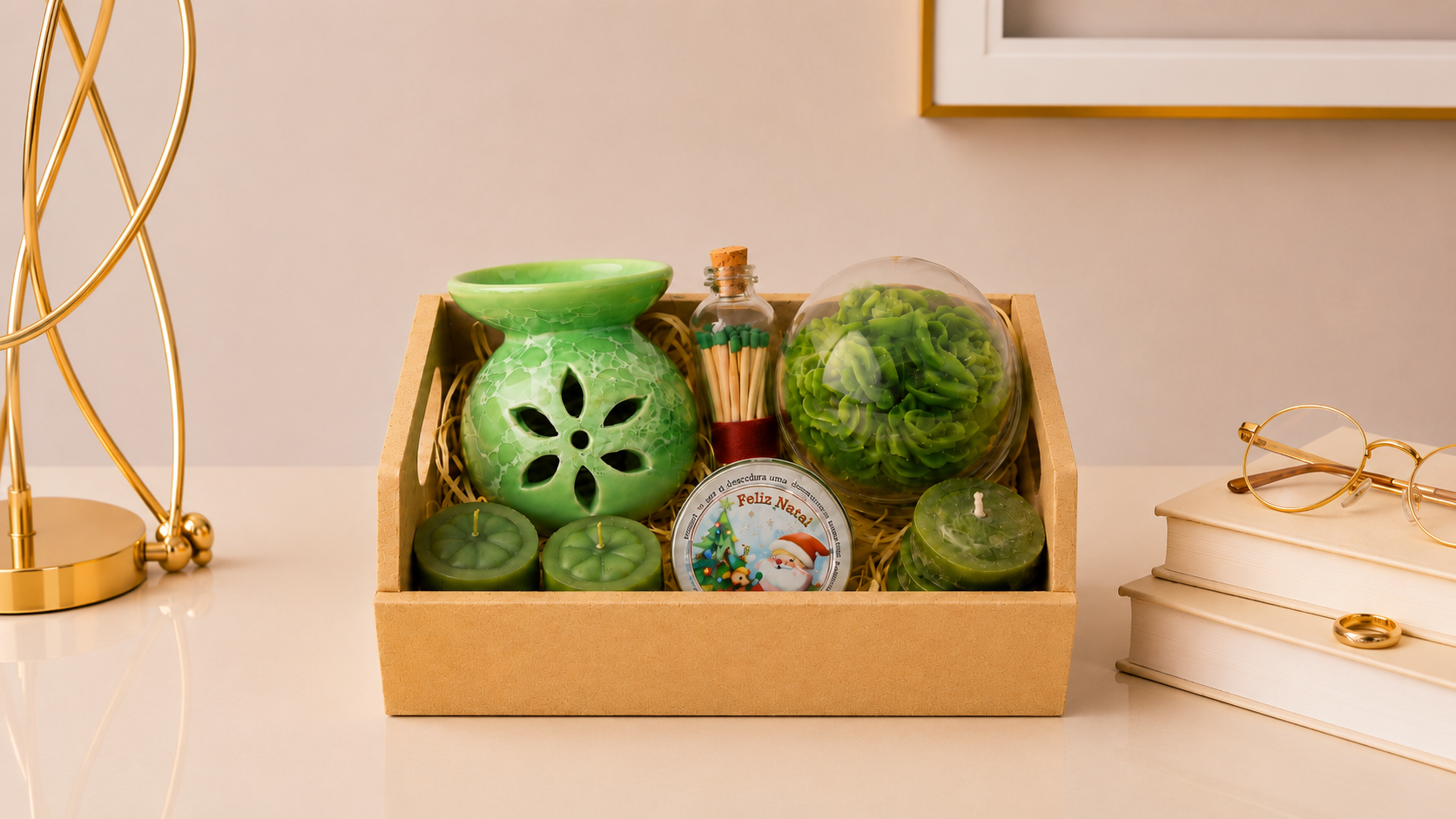 Kit Aromático Decorativo composto por aromatizador cerâmico verde, vela decorativa floral protegida por redoma de vidro, fósforos decorativos em frasco de vidro, mini velas artesanais e lata aromática temática natalina. Os itens estão organizados em uma elegante caixa de presente com acabamento sofisticado, posicionada em ambiente contemporâneo com iluminação suave, detalhes dourados e elementos decorativos que transmitem aconchego, elegância e bem-estar.