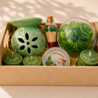 Kit Aromático Decorativo artesanal composto por aromatizador cerâmico verde, vela decorativa floral em formato de rosa sob redoma transparente, fósforos decorativos em frasco de vidro, mini velas aromáticas e lata temática natalina. Os itens estão organizados em uma elegante bandeja decorativa com enchimento de palha, sobre fundo bege claro com iluminação suave e sombras naturais, transmitindo uma atmosfera acolhedora, sofisticada e harmoniosa.