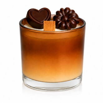 Vela Aromática de Chocolate em copo de vidro degradê nos tons de creme e chocolate, decorada com miniaturas de chocolates em formato de coração e flor sobre a superfície. A peça possui pavio de madeira e acabamento sofisticado, apresentada em fundo branco com iluminação suave para destaque dos detalhes artesanais.