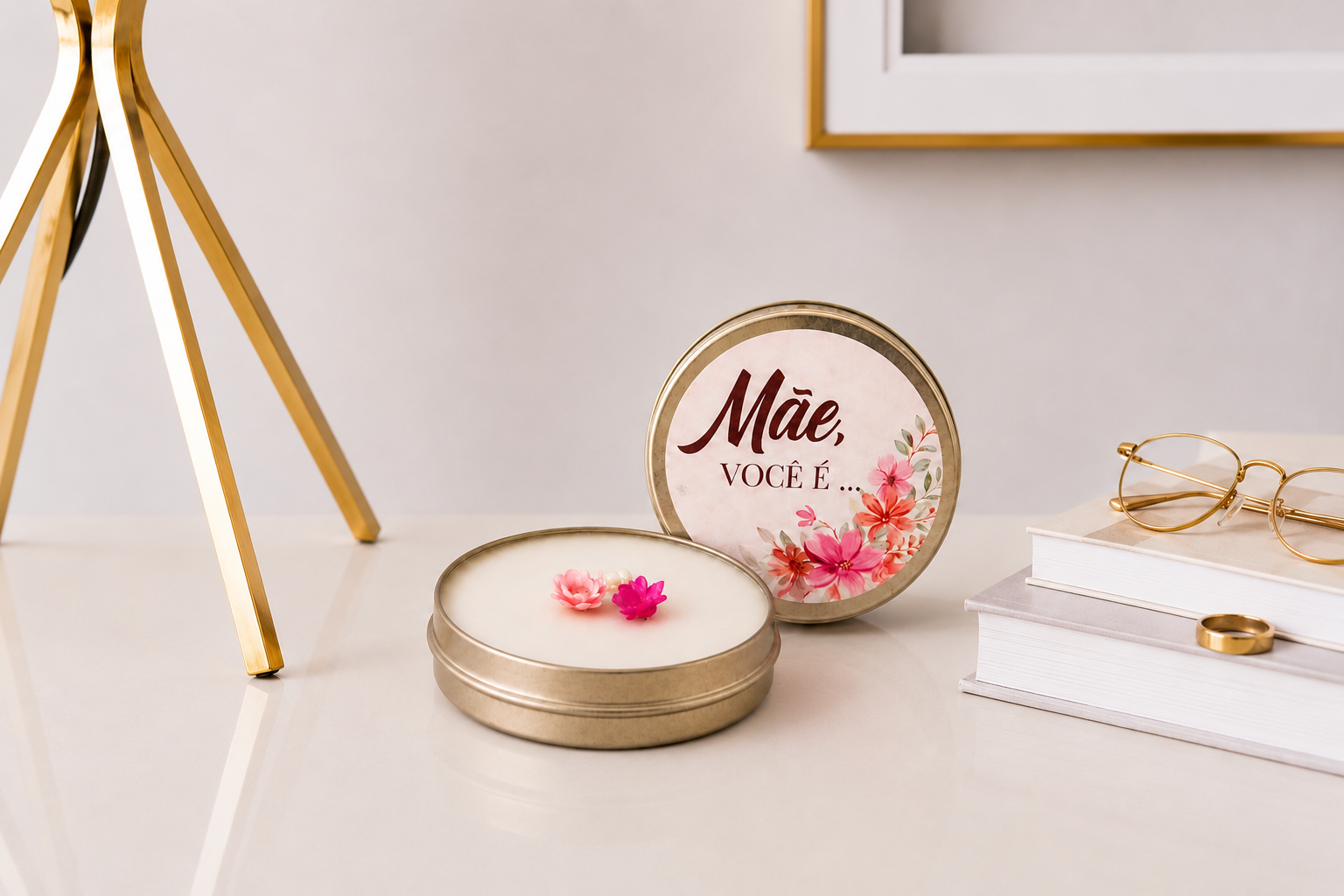 Vela Aromática Dia das Mães em lata metálica dourada com tampa personalizada contendo a frase “Mãe, você é...”, apresentada em ambiente sofisticado com livros decorativos, óculos dourados e iluminação suave.