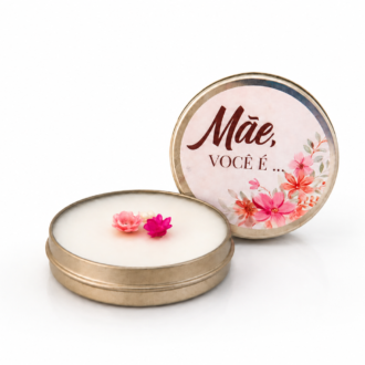 Vela Aromática Dia das Mães em lata metálica dourada com tampa personalizada contendo a frase “Mãe, você é...”, decorada com delicadas flores em miniatura e apresentada sobre fundo branco para catálogo de produtos.