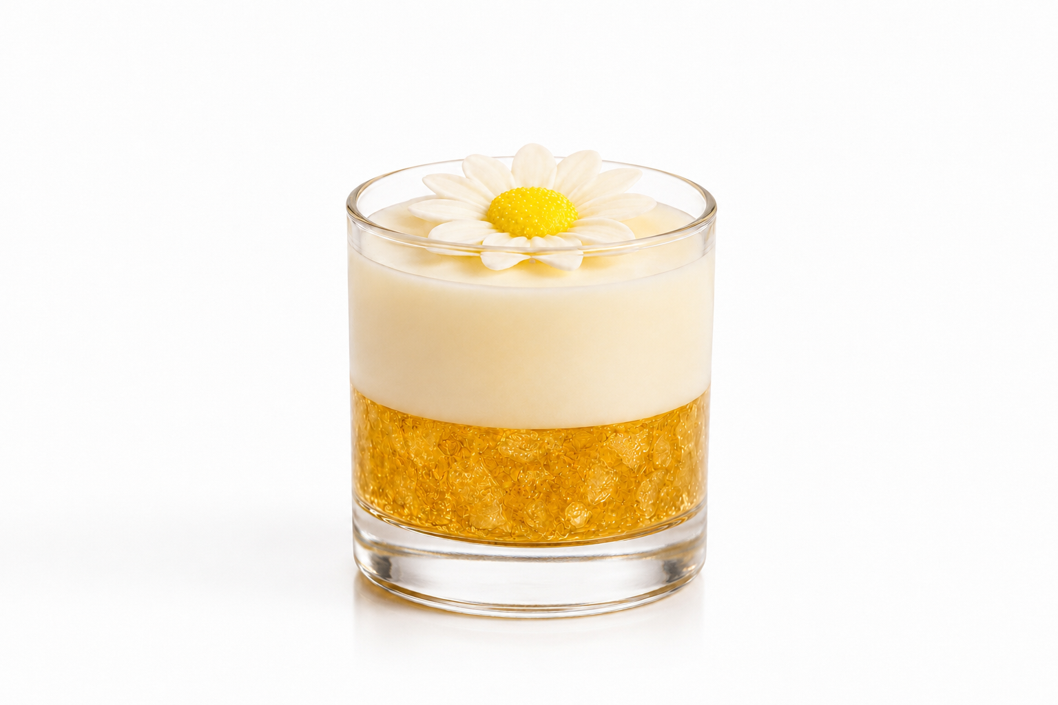 Vela Aromática Margarida artesanal em copo de vidro transparente, composta por uma camada inferior dourada com cristais decorativos e uma camada superior em tom creme suave. No topo, uma delicada margarida branca com centro amarelo complementa o design elegante da peça. A vela está fotografada sobre fundo branco, destacando seus detalhes, transparência do vidro e acabamento sofisticado.