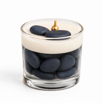 Vela Aromática Quartzo Azul em copo de vidro transparente, composta por pedras decorativas azul-escuras na base e camada superior de cera branca cremosa. A vela possui pavio metálico dourado centralizado e duas pedras azuis decorativas sobre a superfície. A imagem foi produzida em fundo branco puro, destacando os detalhes do vidro, das pedras e do design minimalista da peça.