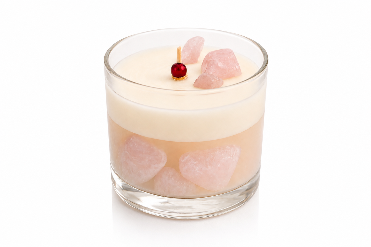 Vela Aromática Quartzo Rosa em copo de vidro transparente, composta por uma camada superior de cera branca cremosa e uma base rosada translúcida com pedras decorativas inspiradas no quartzo rosa. A vela está fotografada em fundo branco, destacando os detalhes delicados dos cristais e o acabamento sofisticado da peça.