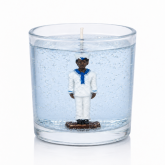 Vela artesanal em gel azul-claro transparente com figura de Marinheiro em uniforme branco e detalhes azuis posicionada no centro do recipiente de vidro cilíndrico. A composição destaca a transparência do gel, as pequenas bolhas decorativas e a estética marítima associada à proteção, serenidade e equilíbrio.