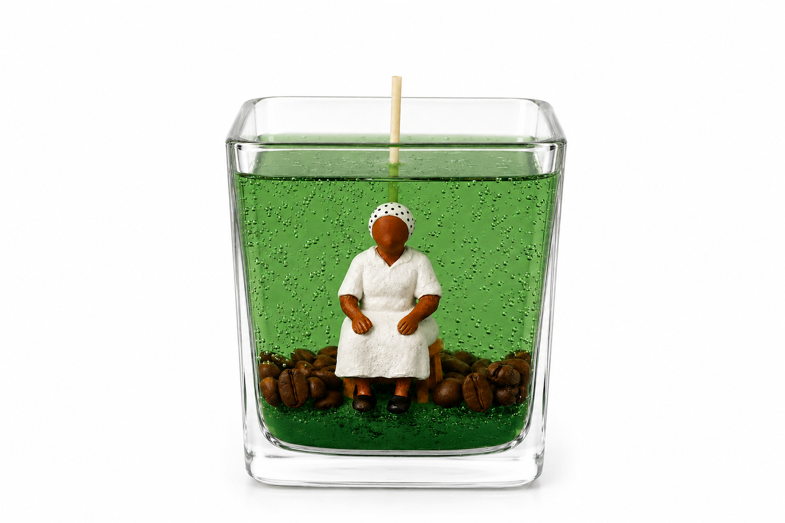 Vela em Gel Preta Velha artesanal em copo de vidro quadrado com parafina em gel verde translúcida, escultura de Preta Velha sentada e grãos de café decorativos. A peça está fotografada em fundo branco, destacando os detalhes da composição e do acabamento artesanal.