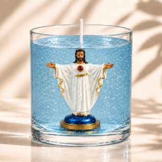 Vela em gel azul transparente com microbolhas decorativas em recipiente cilíndrico de vidro. No interior da vela encontra-se uma imagem do Sagrado Coração de Jesus com vestes brancas e detalhes dourados, braços abertos em gesto de acolhimento e coração vermelho destacado no peito. A composição está sobre fundo claro com sombras suaves de folhagens, destacando o aspecto artesanal, religioso e elegante da peça.