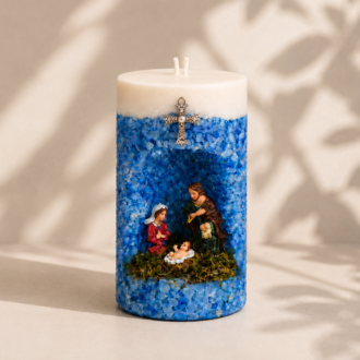 Vela em Gruta Sagrada Família artesanal decorada em tons de azul e branco, com nicho central contendo as imagens de Maria, José e o Menino Jesus. A peça apresenta acabamento texturizado com cristais decorativos azuis, cruz metálica ornamentada na parte frontal e dois pavios, destacando uma composição religiosa delicada e elegante.