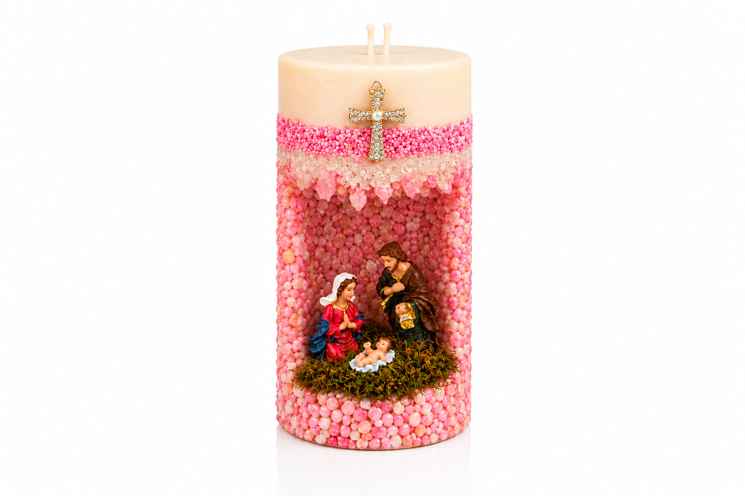 Vela em Gruta Sagrada Família artesanal decorada em tons de rosa e branco, com nicho central contendo as imagens de Maria, José e o Menino Jesus. A peça possui acabamento texturizado com pequenas esferas decorativas, detalhe de cruz dourada com pedrarias na parte frontal e dois pavios na superfície.