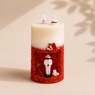 Vela Gruta de Zé Pilintra artesanal decorada com pedras vermelhas e brancas, miniatura de Zé Pilintra, dados, cartas e bengala, inspirada na espiritualidade brasileira.